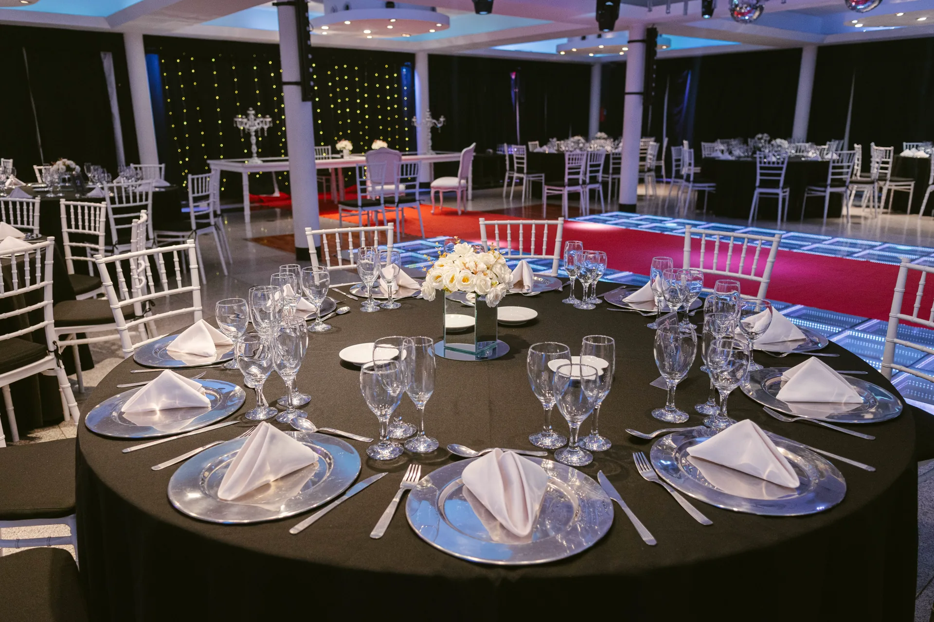 Mesas redondas montadas con mantelería y cristalería para casamiento